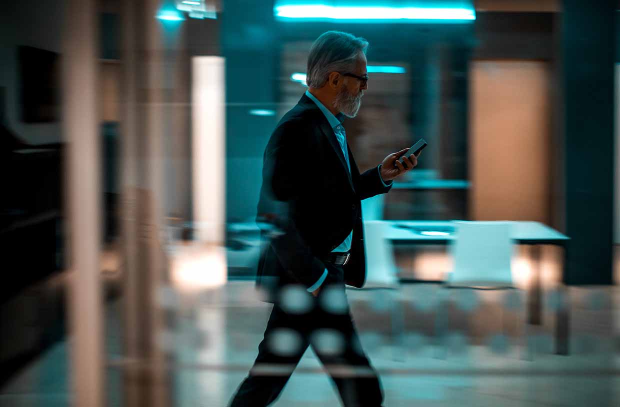 Un uomo guarda il proprio telefono mentre cammina